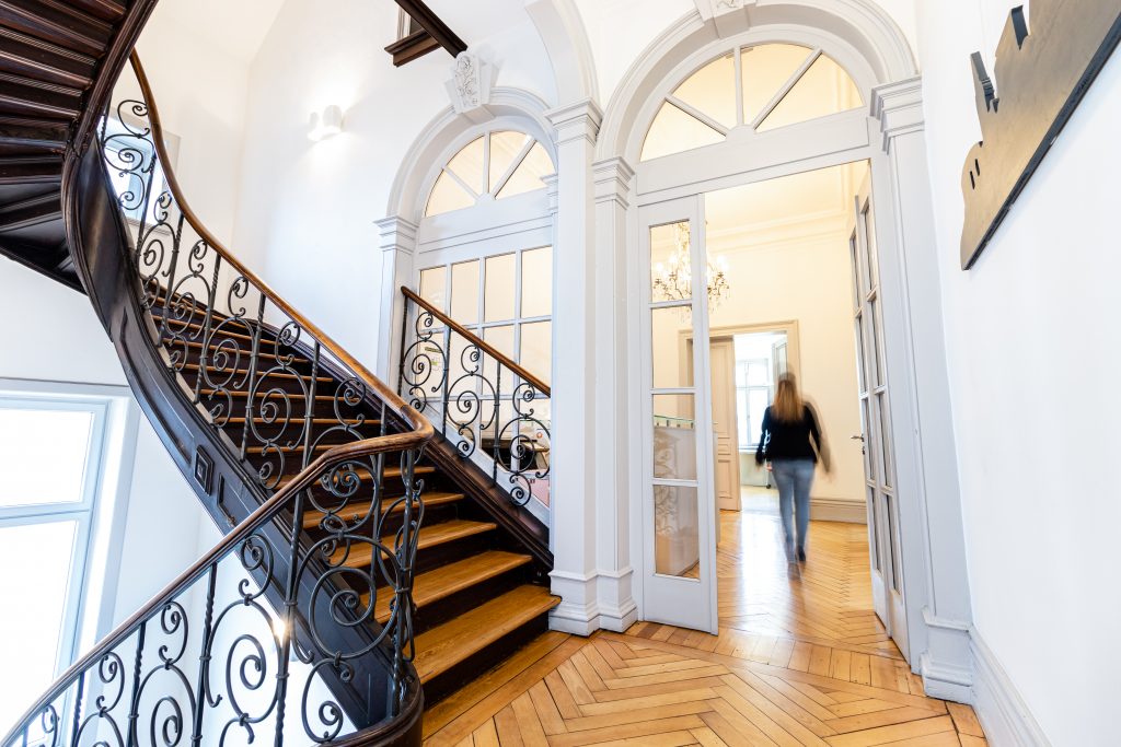 Das Bild zeigt eine Mitarbeiterin auf dem Flur des Bürogebäudes von Thees und Partner