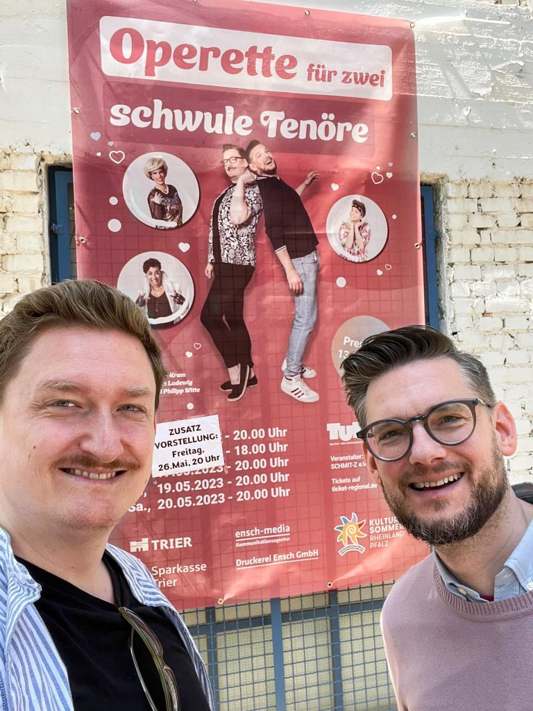 Bild zeigt zwei Personen, die vor einem Banner stehen