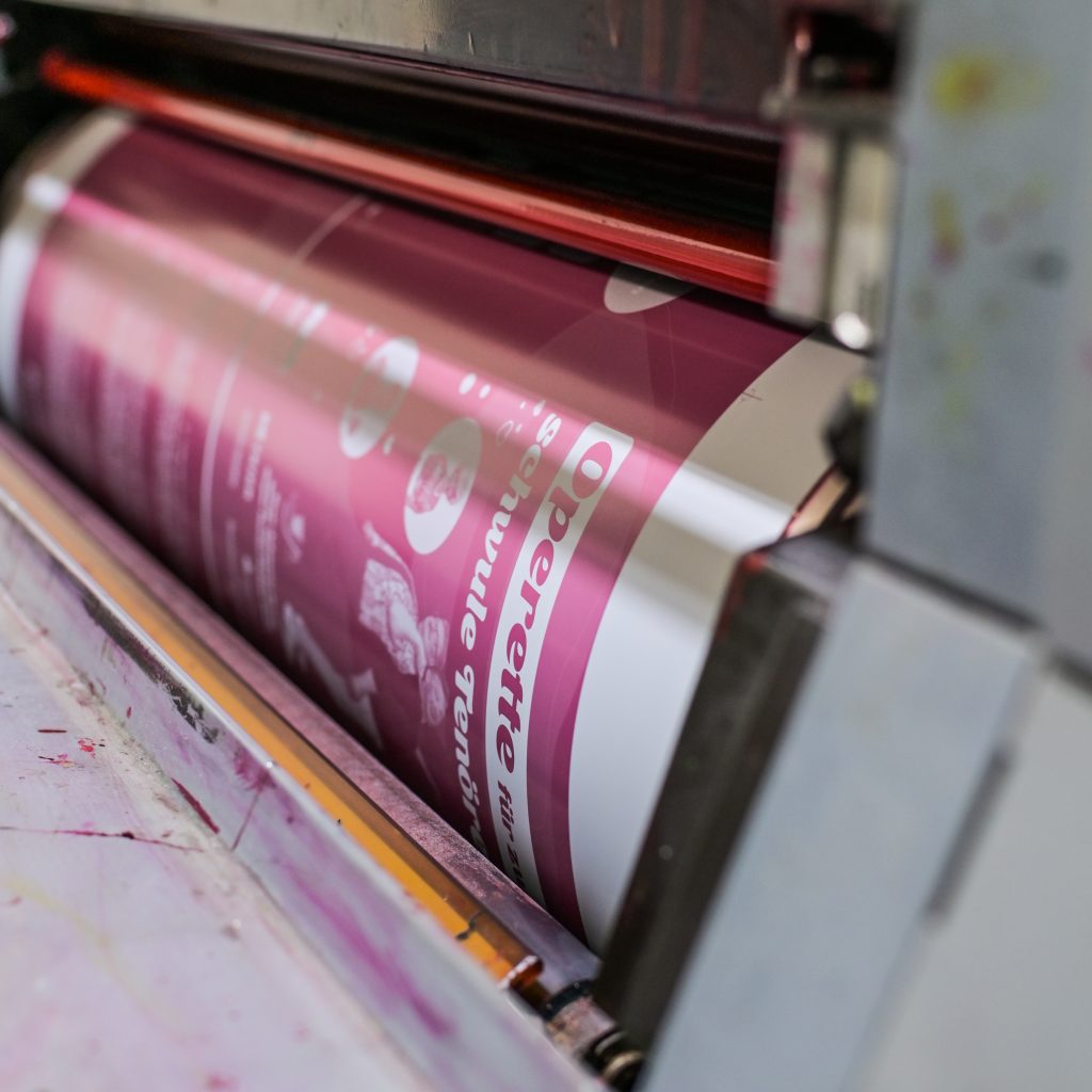 Bild zeigt wie ein Plakat in einer Offsetdruckmaschine gedruckt wird