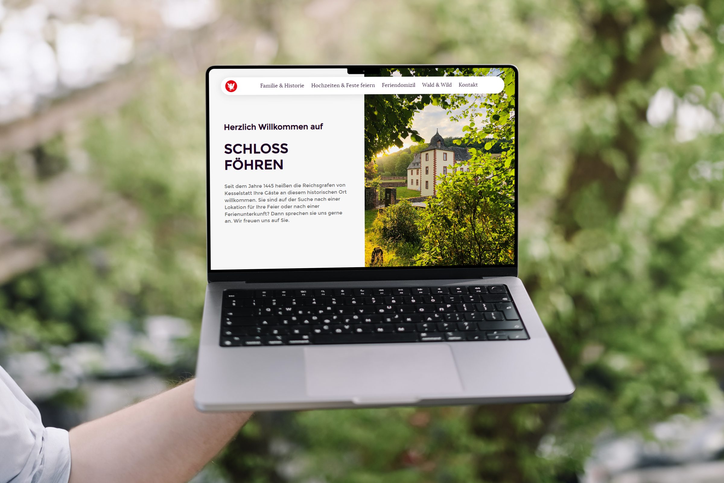 Ansicht der Website auf einem Notebook das von einer Hand gehalten wird